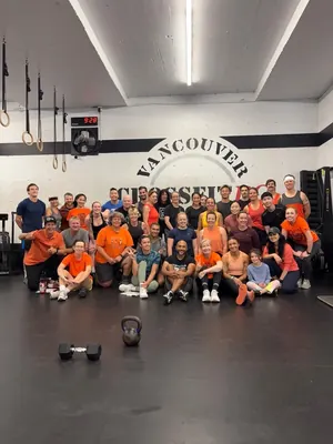 CrossFit BC members in orange shirts under the Vancouver CrossFit BC wall logo
