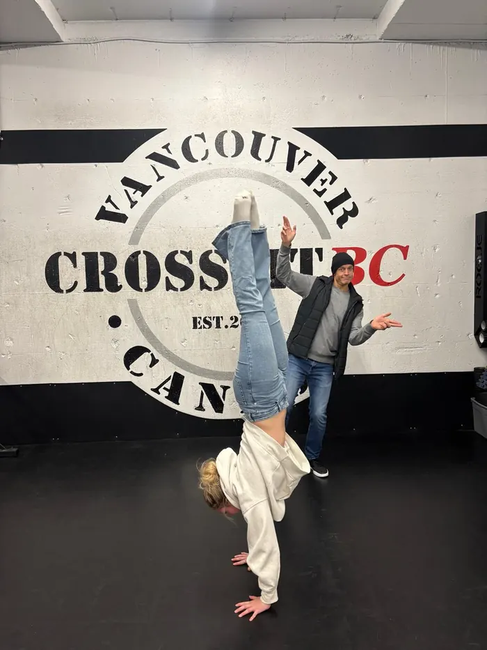 Member holding a handstand under the CrossFit BC wall logo