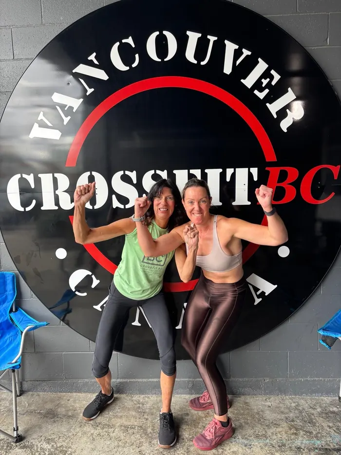 Two CrossFit BC members flexing under the gym sigil