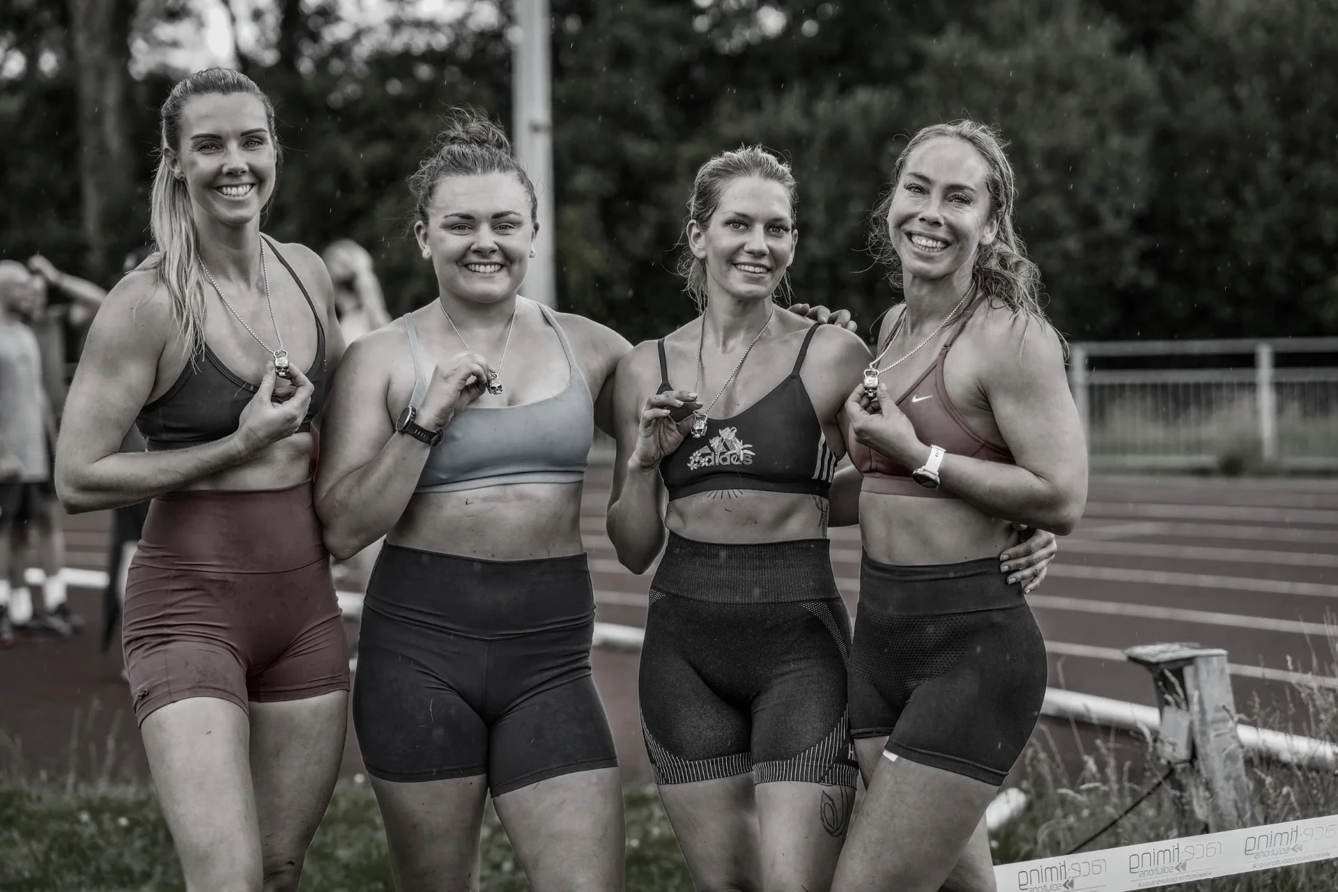 Four Deadly Dozen finishers holding their medals on the track